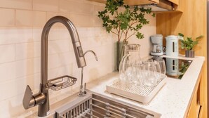A modern kitchen with a stainless steel sink, wooden cabinets, and a coffee machine.