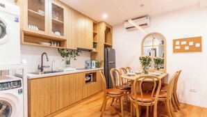 A kitchen with wooden cabinets, a sink, a washing machine, and a dining area with wooden chairs and a table.