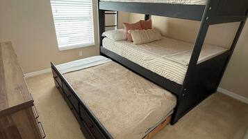 A bunk bed with a wooden frame, a desk, and a window with blinds.