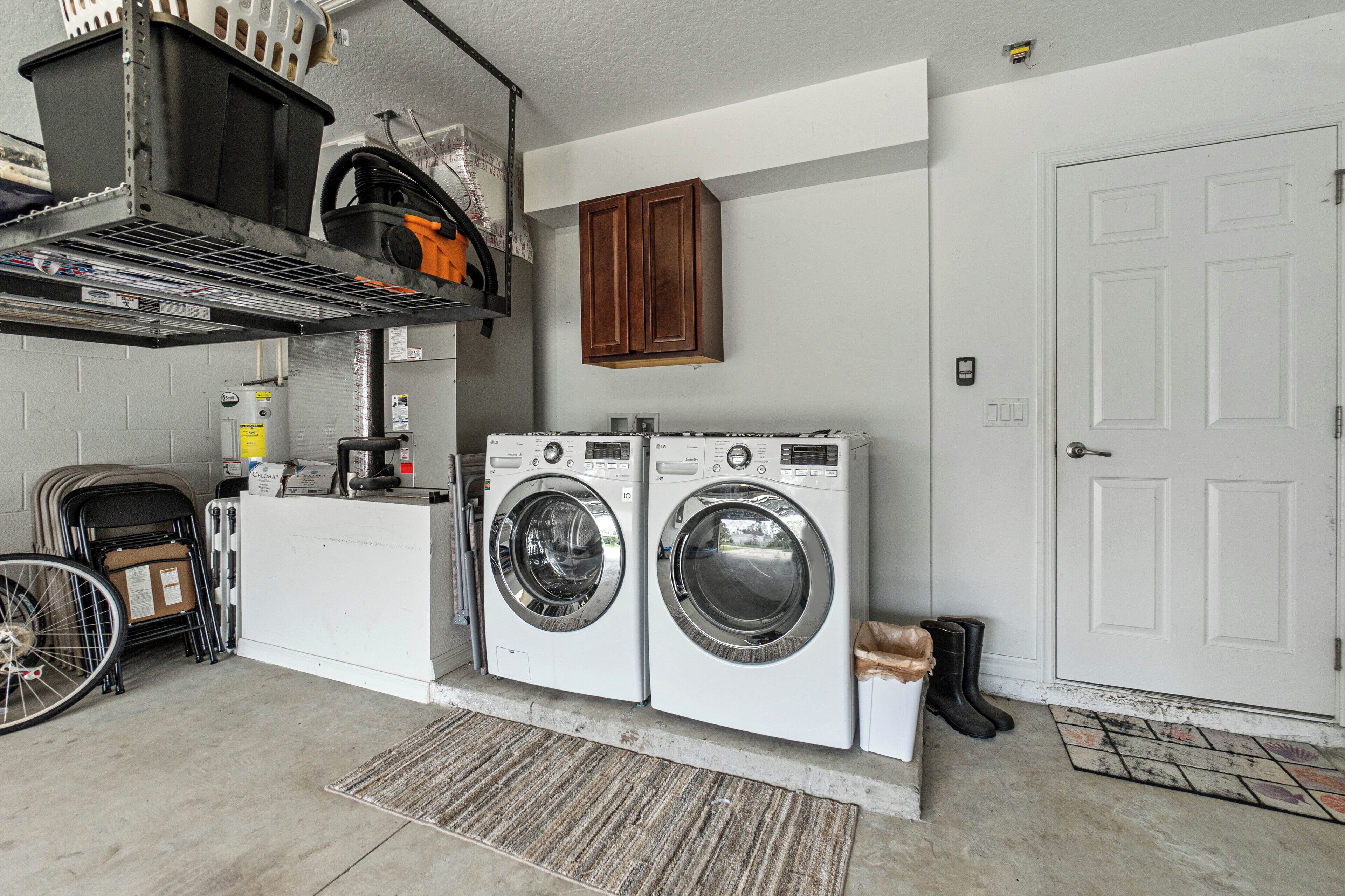 A laundry area with two front-loading washing machines, a drying rack, and a utility cart.