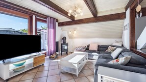 Un salon comprenant un téléviseur, un canapé, une table basse et une grande fenêtre.
