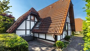 Une maison traditionnelle à colombages, avec un toit en pente, un petit jardin et un chemin pavé.