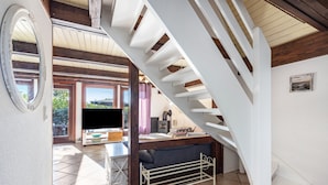 Un escalier menant à un balcon, un canapé et un téléviseur dans un espace de vie.
