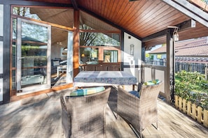 Eine Terrassengestaltung mit Korbmöbeln, einem Tisch und einer Holzbeschichtung.