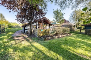 Ein Haus mit überdachter Veranda, einem Garten mit Holzzaun und einem Weg zum Eingang.