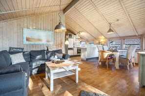 A cozy interior with a wooden ceiling, a sofa, a dining table, and a kitchen area. - Holiday Home 'Möwe' with Private Terrace, Private Garden and Wi-Fi (Hollern-Twielenfleth)
