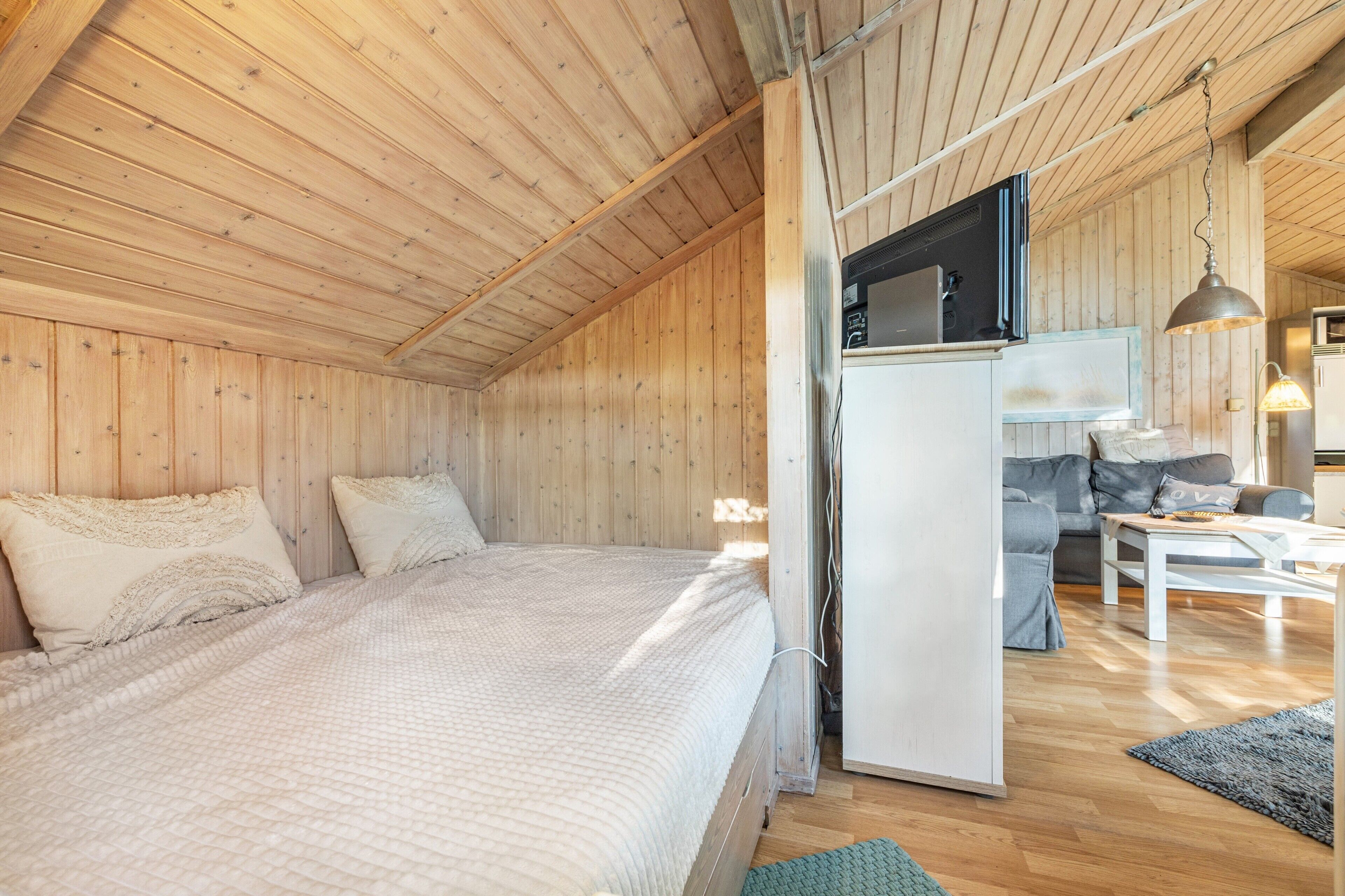 Ein Holzinnenraum mit einem Bett, einer Küchenzeile und einer Sitzecke.