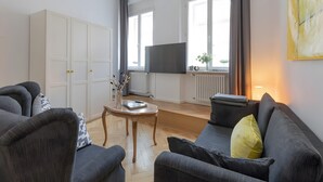 A living room with a sofa, armchairs, a coffee table, a TV, and a radiator. - Apartment 'Fewo Romeo und Julia' with Private Terrace and Wi-Fi (Bamberg)
