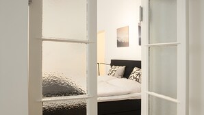 A room with a bed, a wooden floor, and a white door with frosted glass panels. - Apartment 'Fewo Romeo und Julia' with Private Terrace and Wi-Fi (Bamberg)