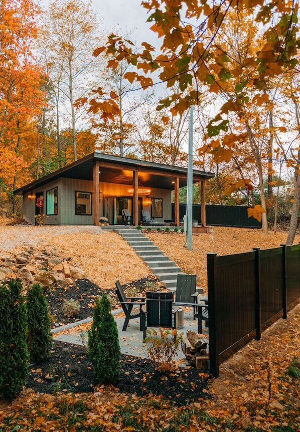 Une maison moderne dotée d’un patio couvert, d’un escalier en pierre et d’une cour clôturée.