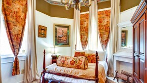 A traditional bedroom with a four-poster bed, a fireplace, and ornate curtains. - Charming 2-bedroom house with WiFi, AC in enchanting downtown Opelousas. (Opelousas)