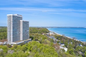 Un hotel de gran altura con diseño moderno, situado cerca de una playa y con vista clara al océano.