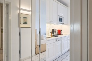 A modern kitchen with white cabinets, a built-in oven, and a coffee maker.