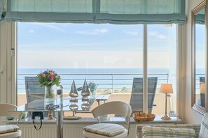 A balcony with a table, chairs, and a view of the sea.
