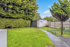 Enjoy a serene outdoor space with a well-manicured lawn, a storage shed, and a tall tree providing shade and seclusion.