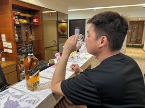 A man sitting at a table with a bottle of Green Label whiskey, a menu, and various items on the table. - Liou Lian Ke Zhan HOTEL (Luodong)