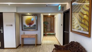 Un vestíbulo espacioso con mostrador de recepción de madera, una obra de arte grande enmarco y una mesa de madera tradicional.