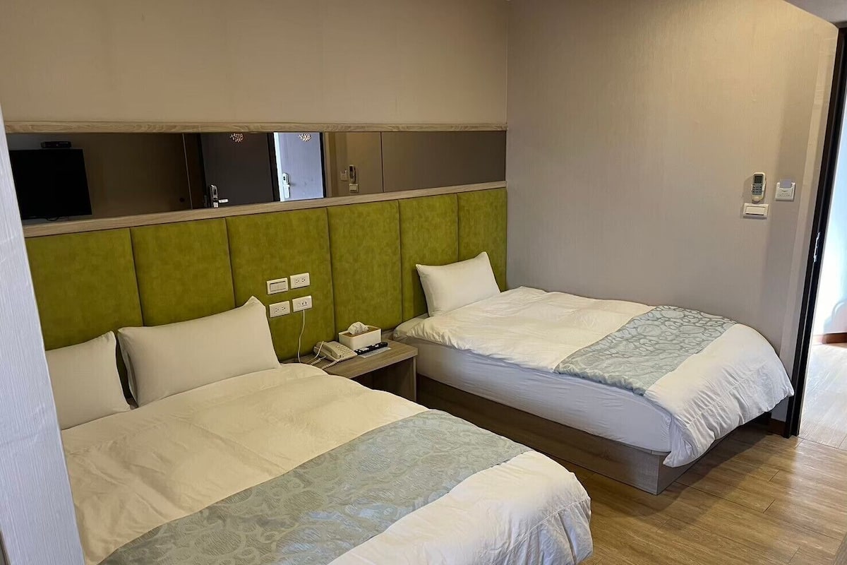 Een hotelkamer met twee bedden, een bureau en een televisie.