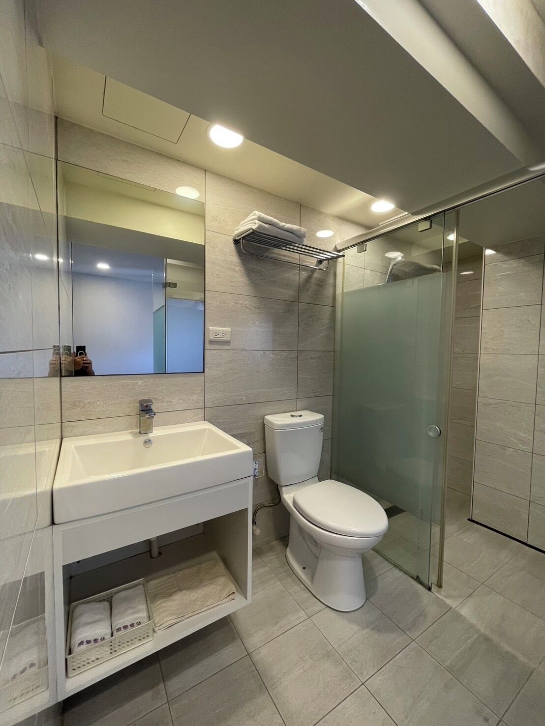 Un baño moderno con cabina de ducha de vidrio, un lavabo blanco y un inodoro.