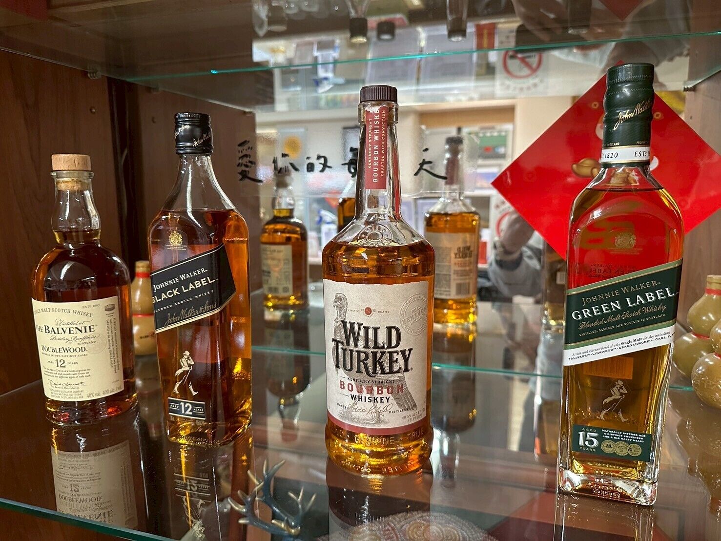 Varias botellas de whisky sobre una estantería de cristal.