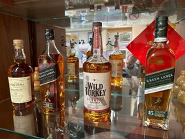 Varias botellas de whisky sobre una estantería de cristal.