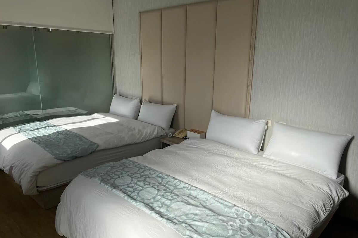 Een hotelkamer met twee bedden, een grote spiegel en een houten hoofdbord.