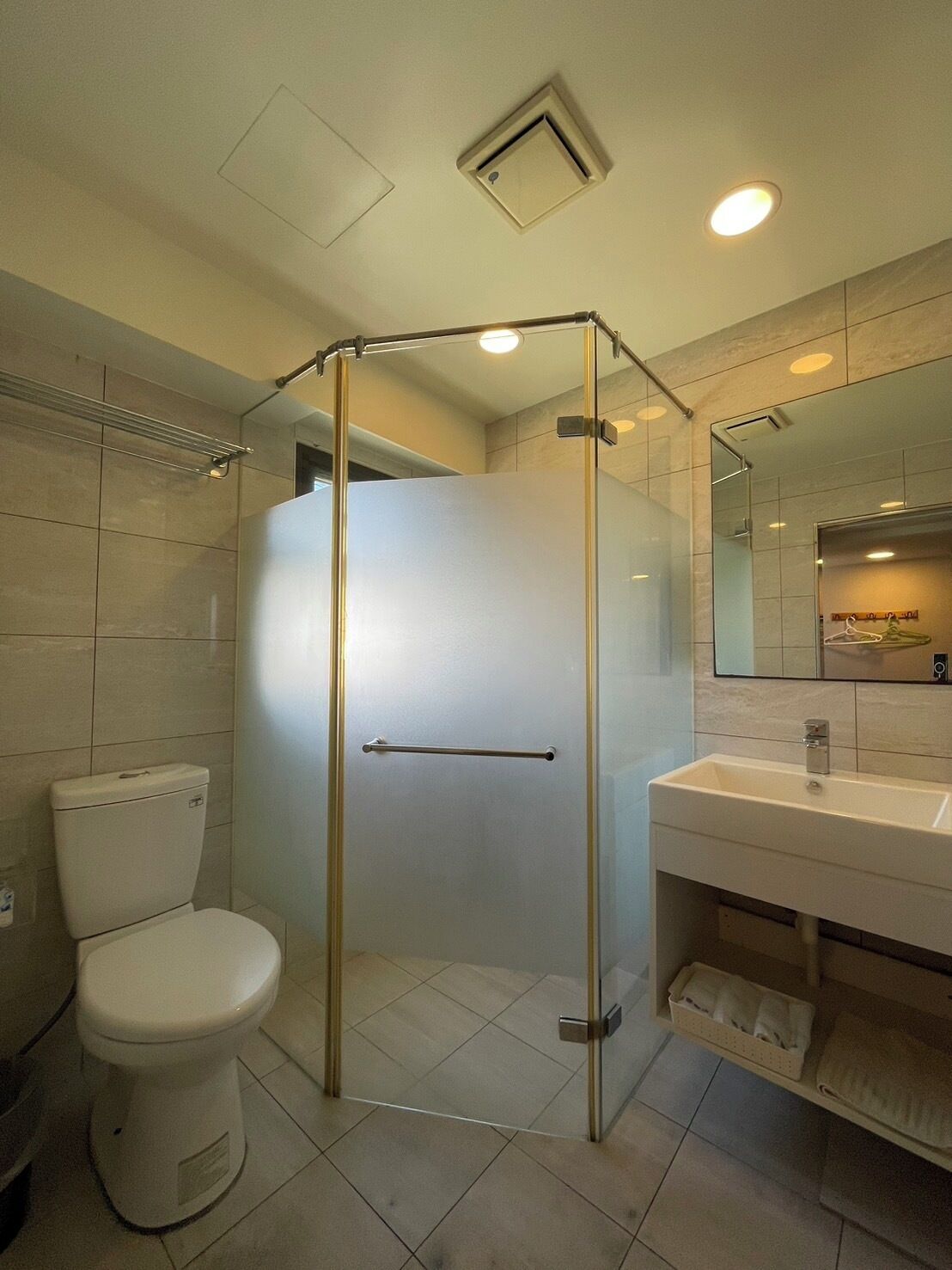 A modern bathroom with a glass-enclosed shower, a toilet, and a sink with a mirror.