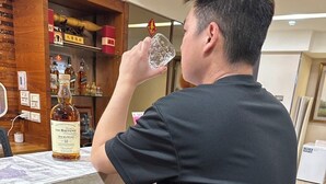 Una persona sentada en un bar con una botella de whisky The Balvenie DoubleWood.