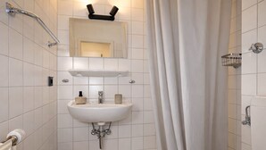 Ein Badezimmer mit weißem Waschbecken, Spiegel und Duschvorhang.