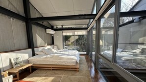 Une chambre moderne avec un grand lit, une table de chevet et une fenêtre donnant sur un balcon.