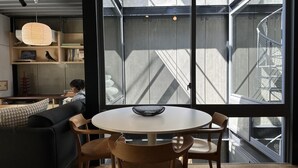 Un intérieur moderne avec une table ronde et des chaises, un canapé et une grande fenêtre donnant sur la ville.
