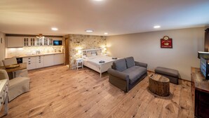 A compact living space with a kitchenette, a bed, a sofa, and a small round table.