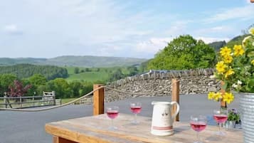 Relax in this serene outdoor seating area overlooking lush green hills and a stone wall.