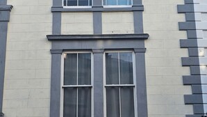 A building facade with two-story windows, a symmetrical design, and a brick pattern on the right side.
