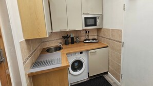 A compact kitchen with a microwave, sink, and washing machine.