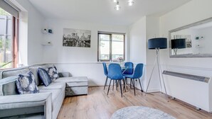 Ein modernes Wohnzimmer mit einer Couch, Sesseln, einem Couchtisch und einer Stehlampe.