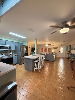 A spacious kitchen with a central island, bar stools, and a dining area with a sofa.