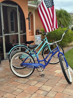 A turquoise bicycle parked in front of a building with an American flag.