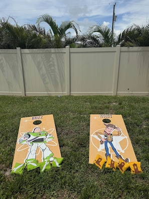 Two wooden boards with cartoon characters on a grassy lawn, with a wooden fence in the background.