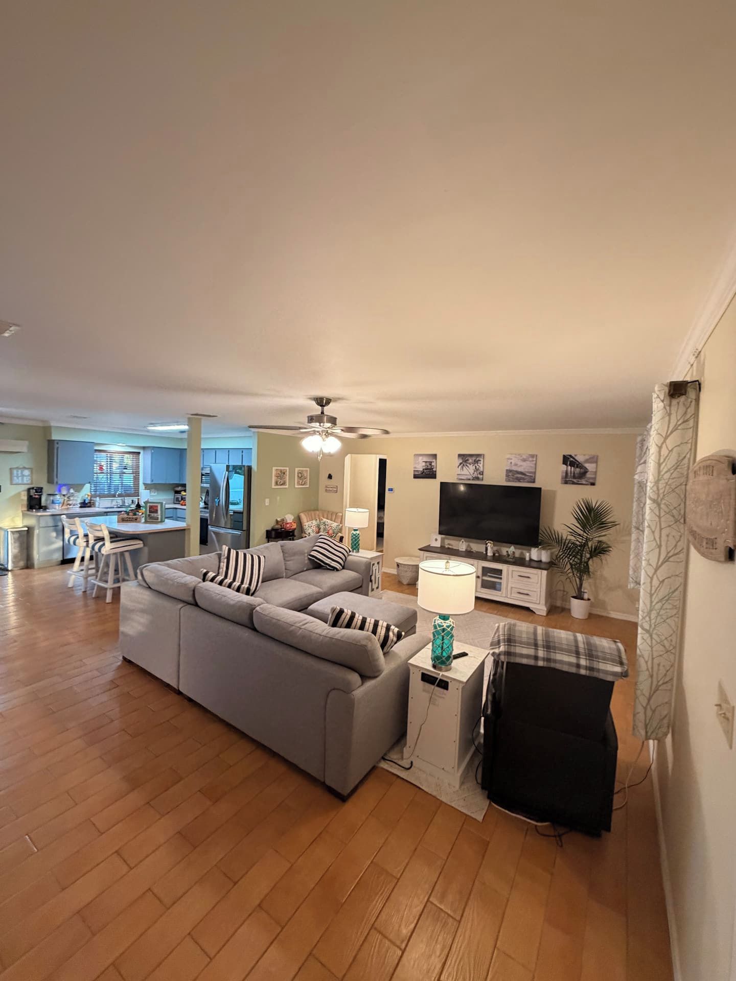 Un salon avec un canapé gris, un téléviseur et un ventilateur de plafond.