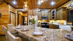 A kitchen with granite countertops, wooden cabinets, and a central island with seating.