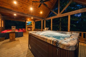 Terraza de madera con jacuzzi, asientos al aire libre y una chimenea.