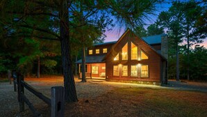 A log cabin with a stone foundation, large windows, and a wooden deck.