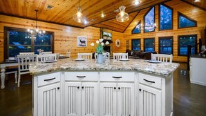 A spacious kitchen with a large island, wooden walls, and large windows.