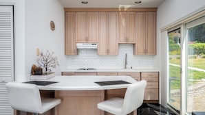 Une cuisine moderne avec des meubles en bois, un plan de travail blanc et une grande fenêtre.