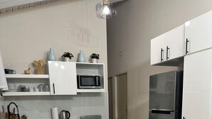 Une cuisine moderne avec des meubles blancs, un réfrigérateur en acier inoxydable, un four à micro-ondes, une cuisinière et un évier.