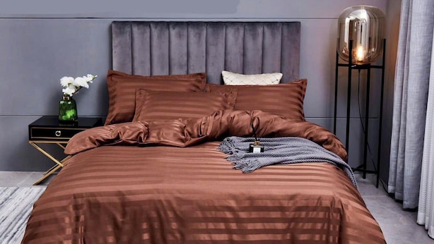 Une chambre à coucher moderne avec un grand lit, une table de chevet, une lampe sur pied et un vase rempli de fleurs.
