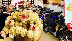 Un hall d’hôtel avec un comptoir d’accueil, une enseigne « HÔTEL » et une rangée de scooters garés.