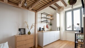 Uma cozinha moderna com armários brancos, teto de madeira e janela com vista para a cidade.