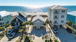 Ein Hotel direkt am Strand mit mehreren Gebäuden, einem Parkplatz und Blick aufs Meer.